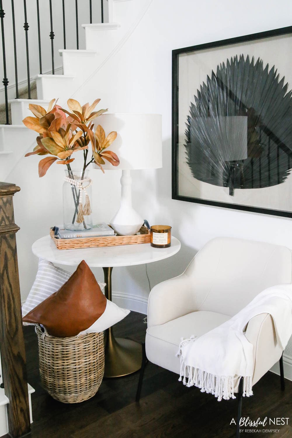 A cozy spot under the stairway. Fall florals, leather pillow, Sea Fan artwork. #ABlissfulNest #fallentry #falldecor