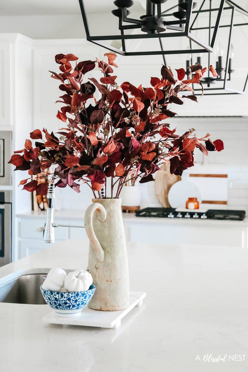 Beautiful fall decor details in this kitchen with burgundy eucalyptus leaves, delicious fall candles, Serena and Lily barstools. #ABlissfulNest #fallkitchen #falldecor #fallideas