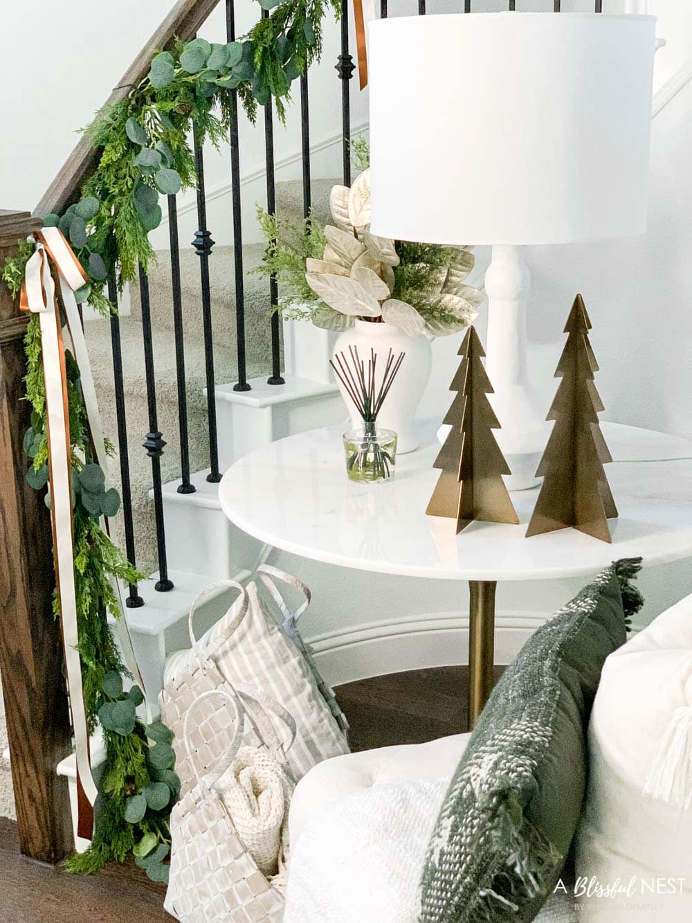 Christmas decor with pillows, baskets, metal trees, and garland on the stairway.