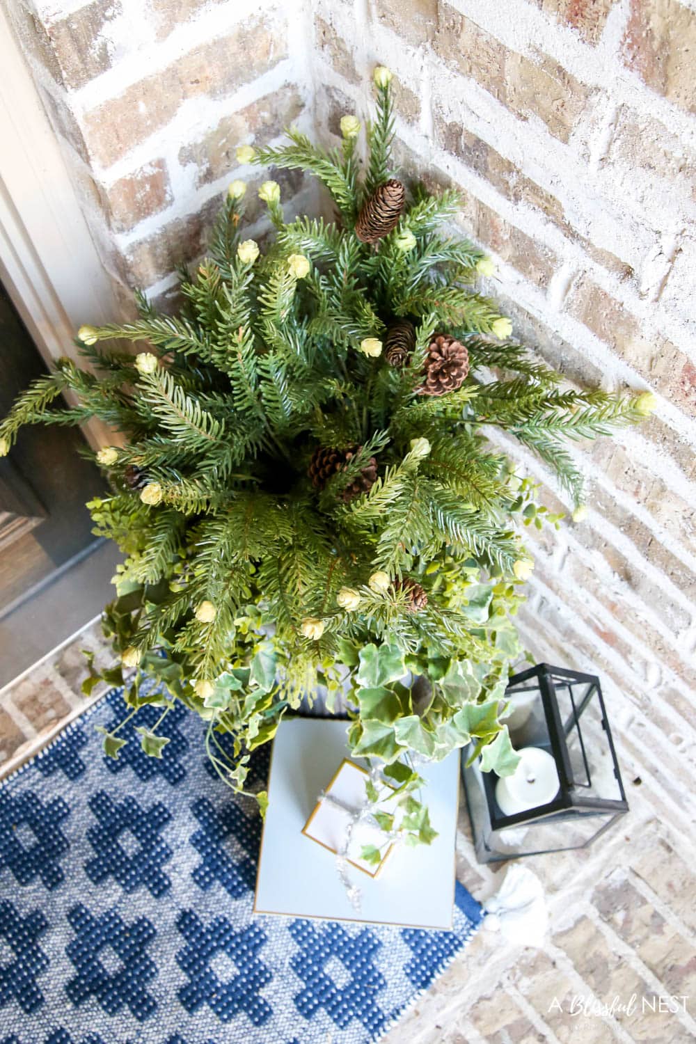 A view from above of a Christmas planter with gift boxes and a black lantern on a front porch.