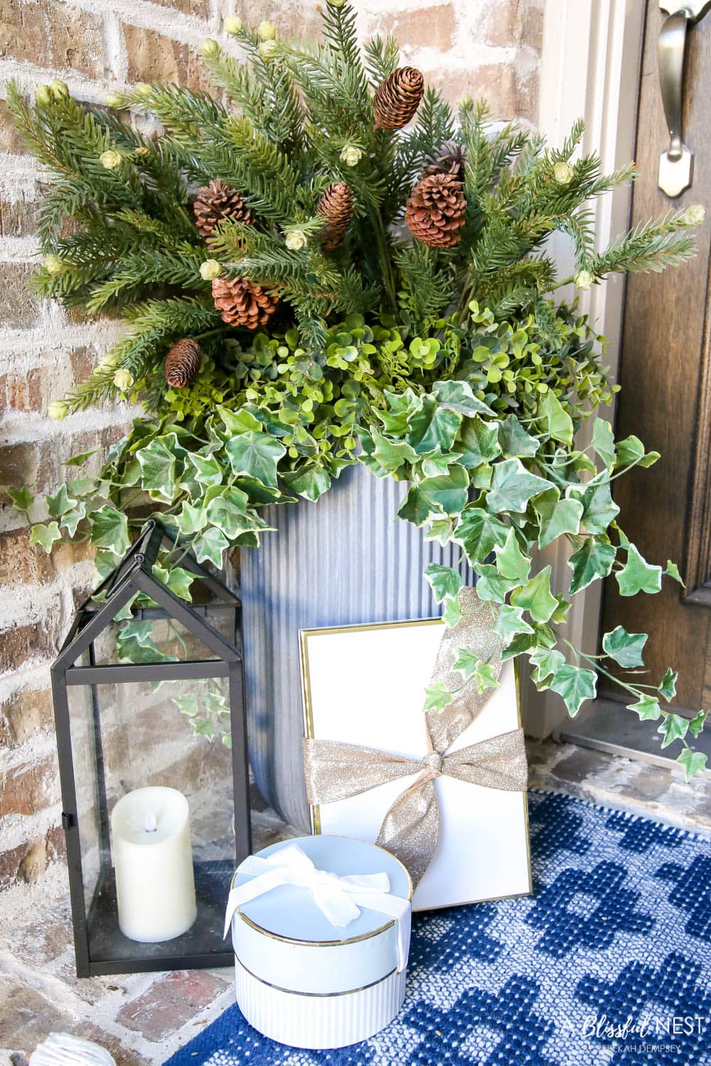 Christmas planter with a black lantern and gift boxes tucked around the base.