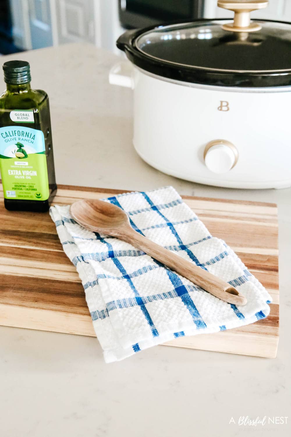 Blue and white dish towel with a wood spoon sitting on a cutting board.