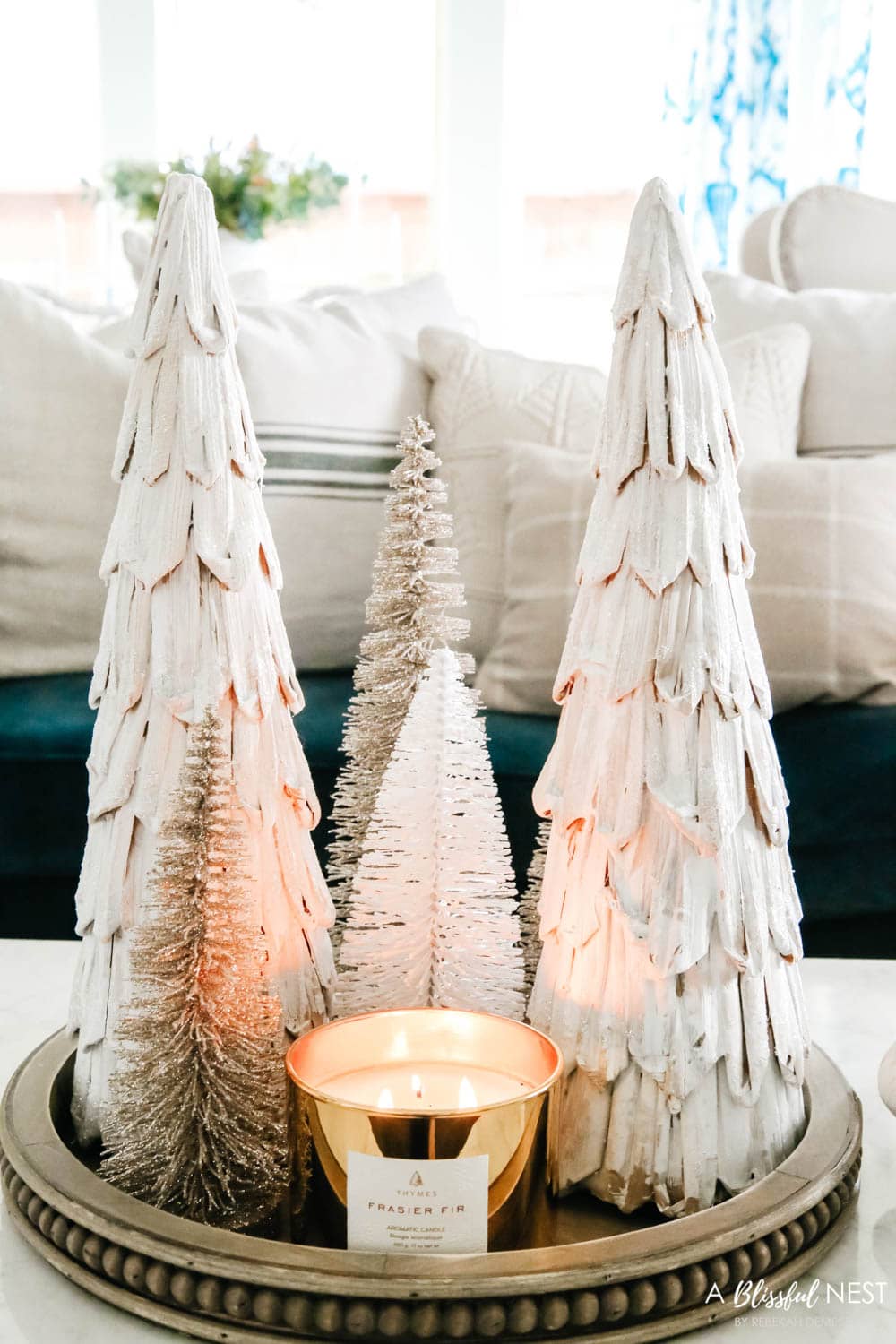 Mini trees clustered on a wood tray with a gold candle