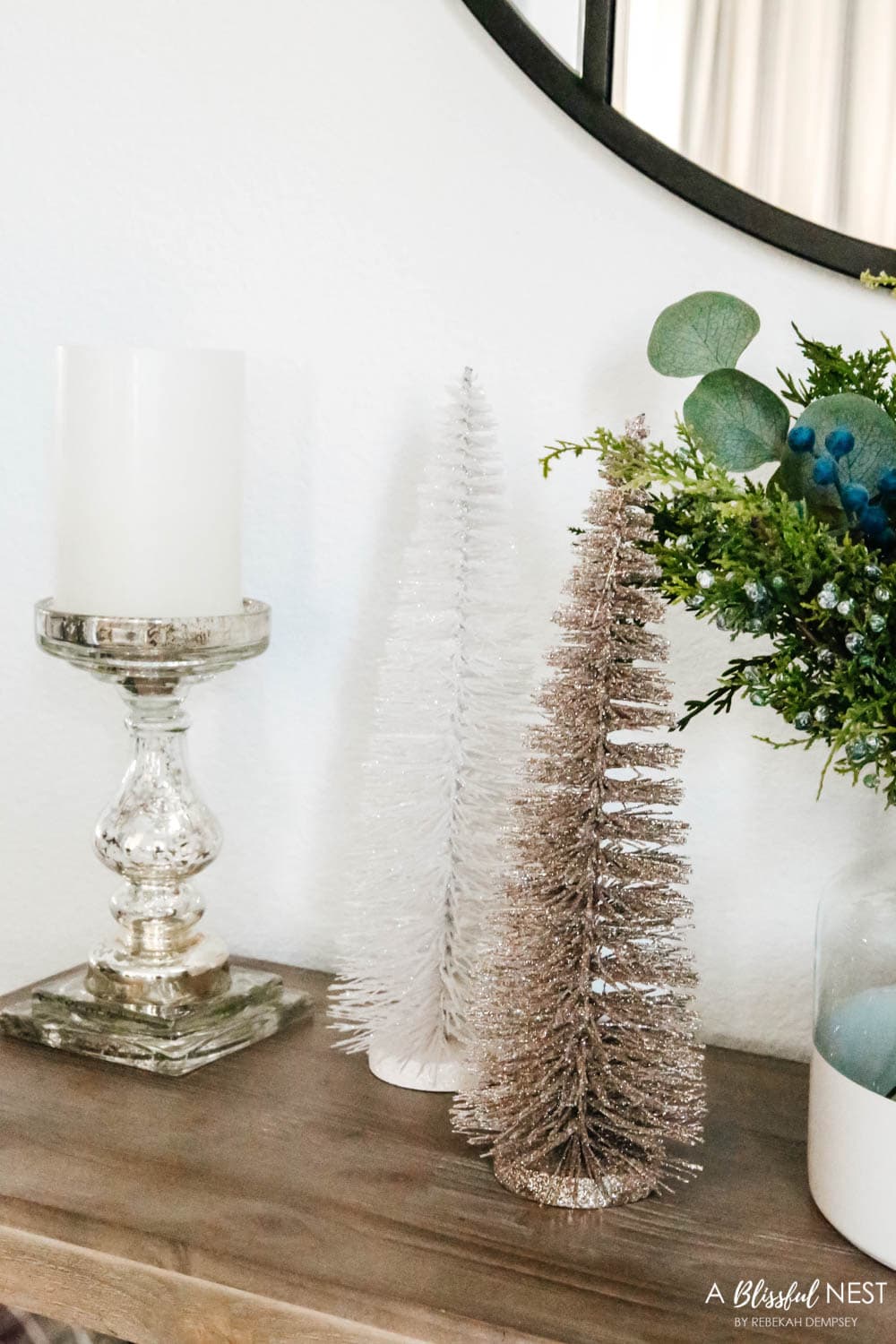 Bottle brush trees next to a mercury glass candlestick on a entryway table