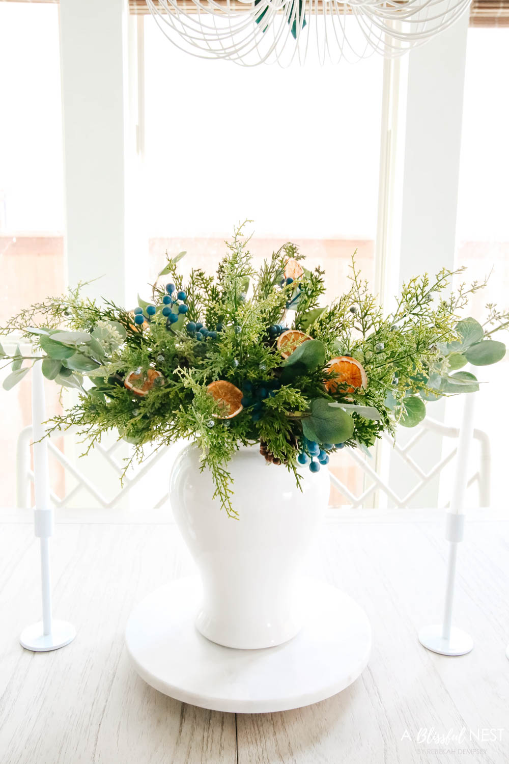 Juniper picks in a white vase with dried orange slices.