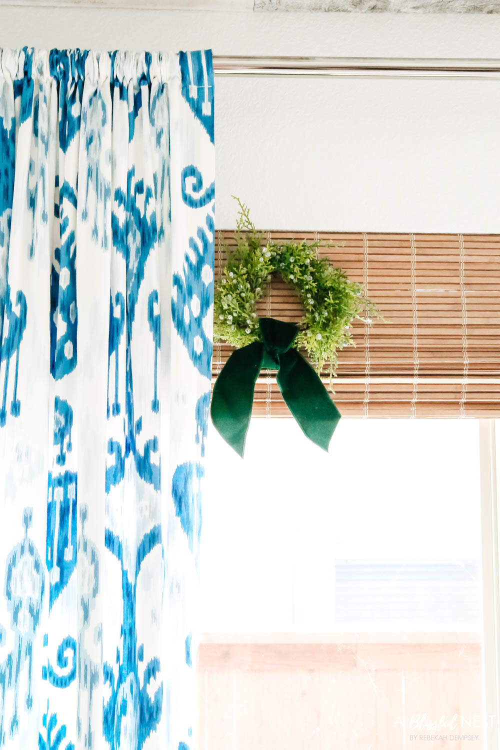 Mini wreaths with green velvet ribbons tied to bamboo shades