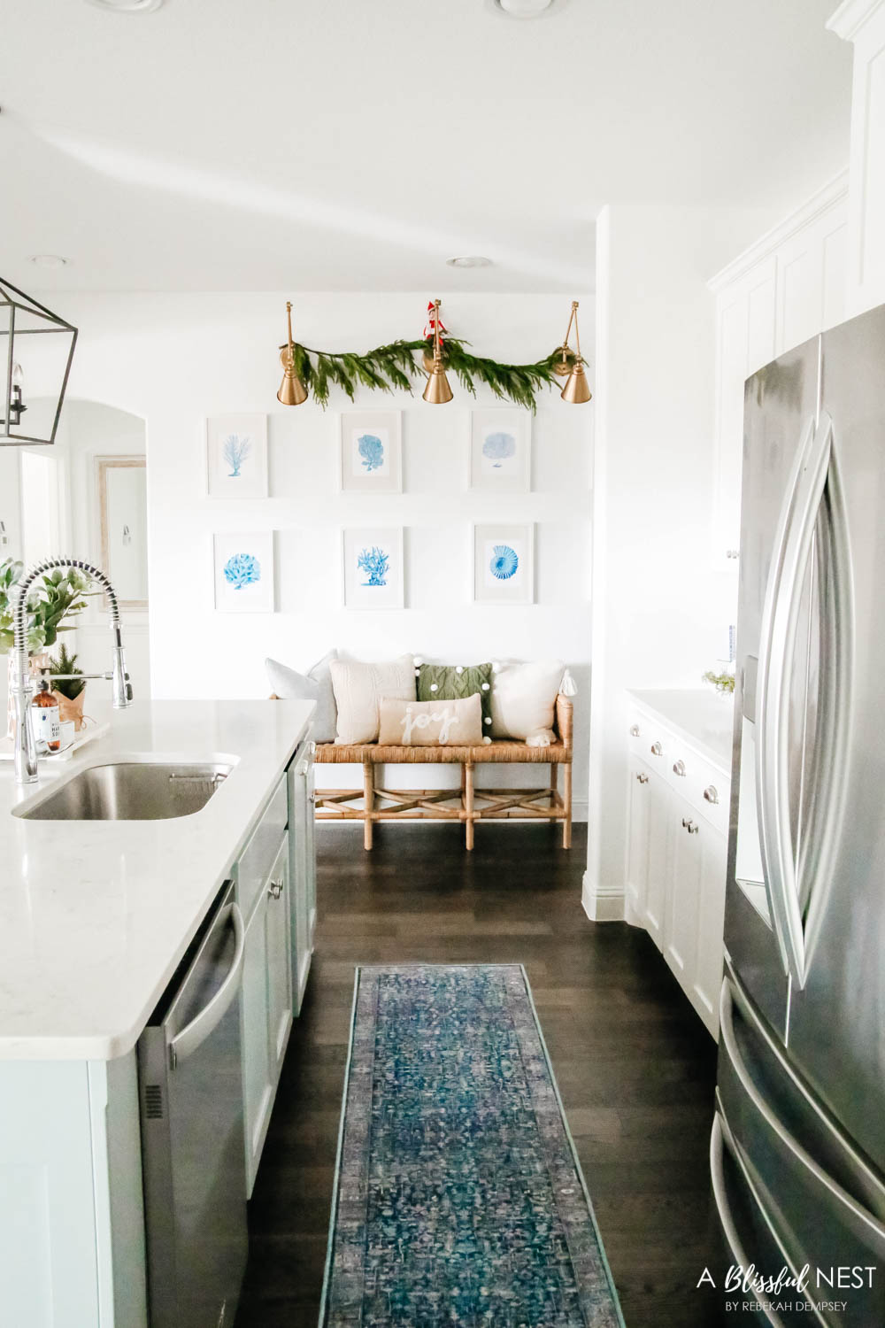 Blue and white coastal art prints on a wall with a rattan bench underneath.