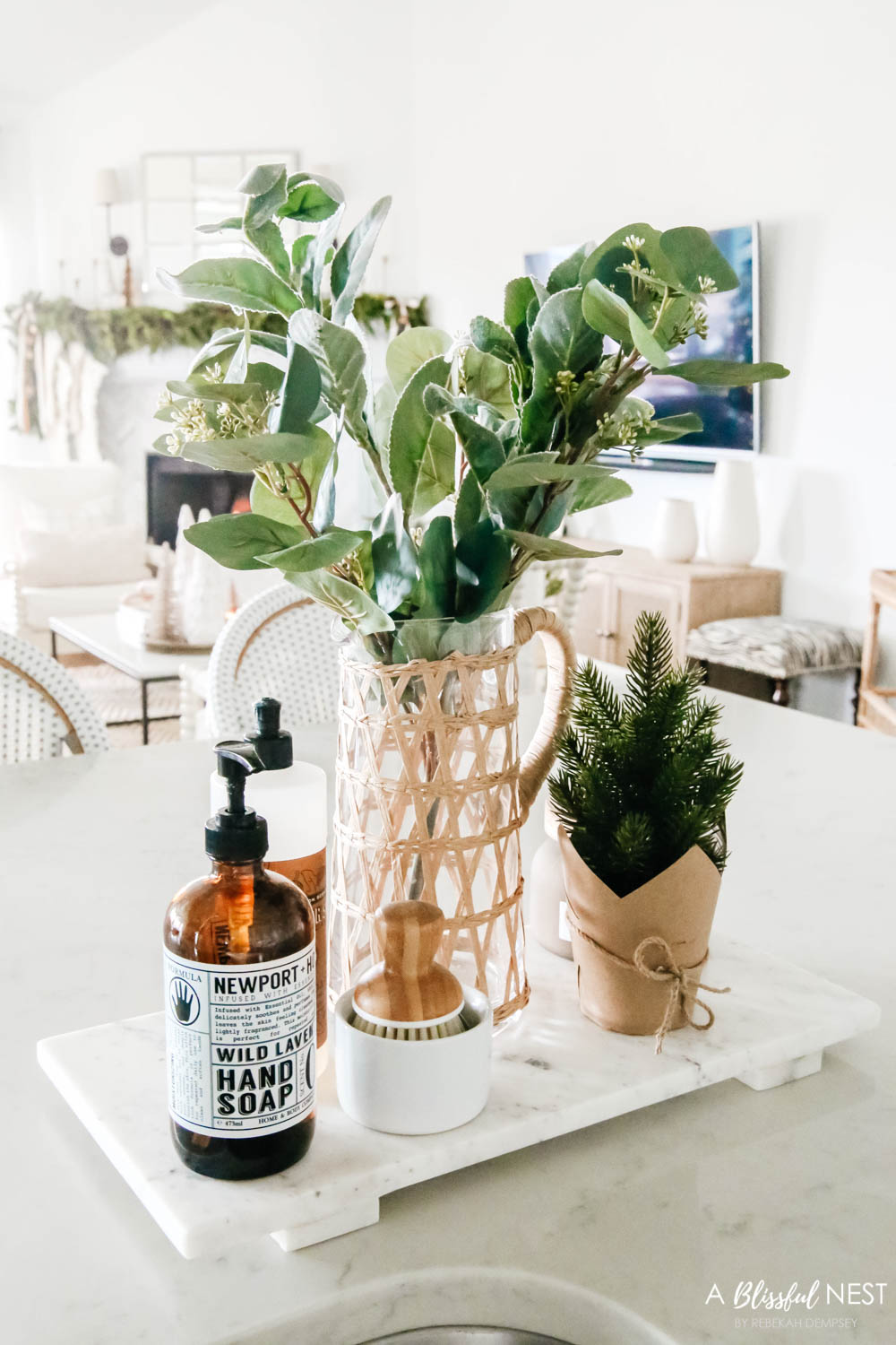 Kitchen faucet with a marble tray with soap and holiday greenery in a vase.