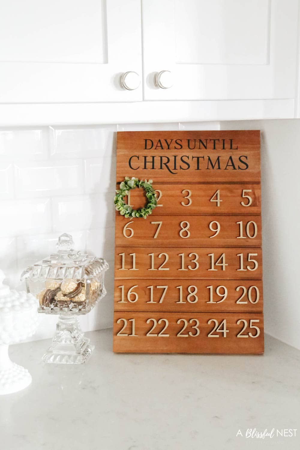 Wood advent calendar with candy dishes next to it on a counter in a kitchen
