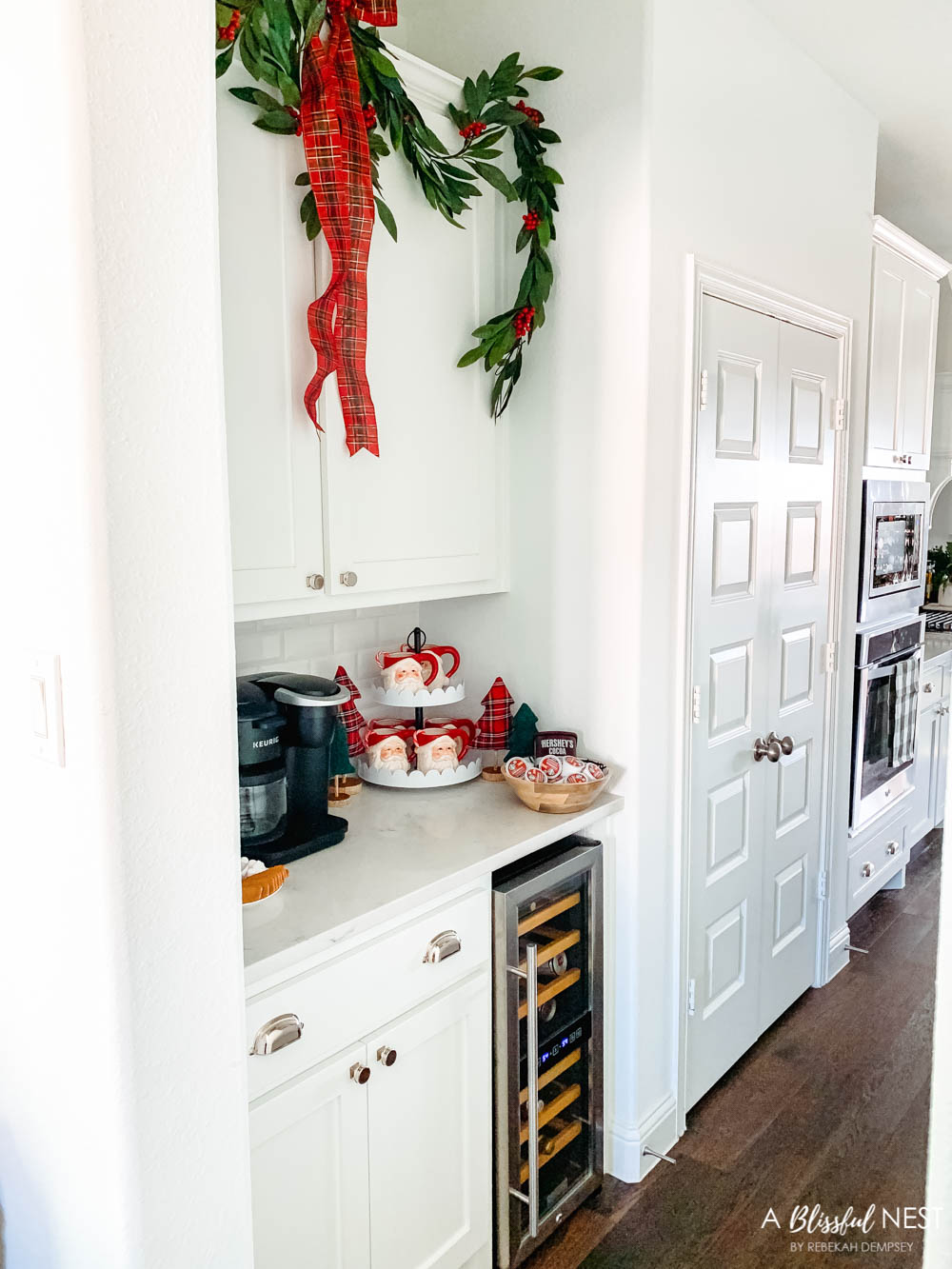 A hot cocoa station in a butlers pantry with santa mugs, graland and a Keurig machine.