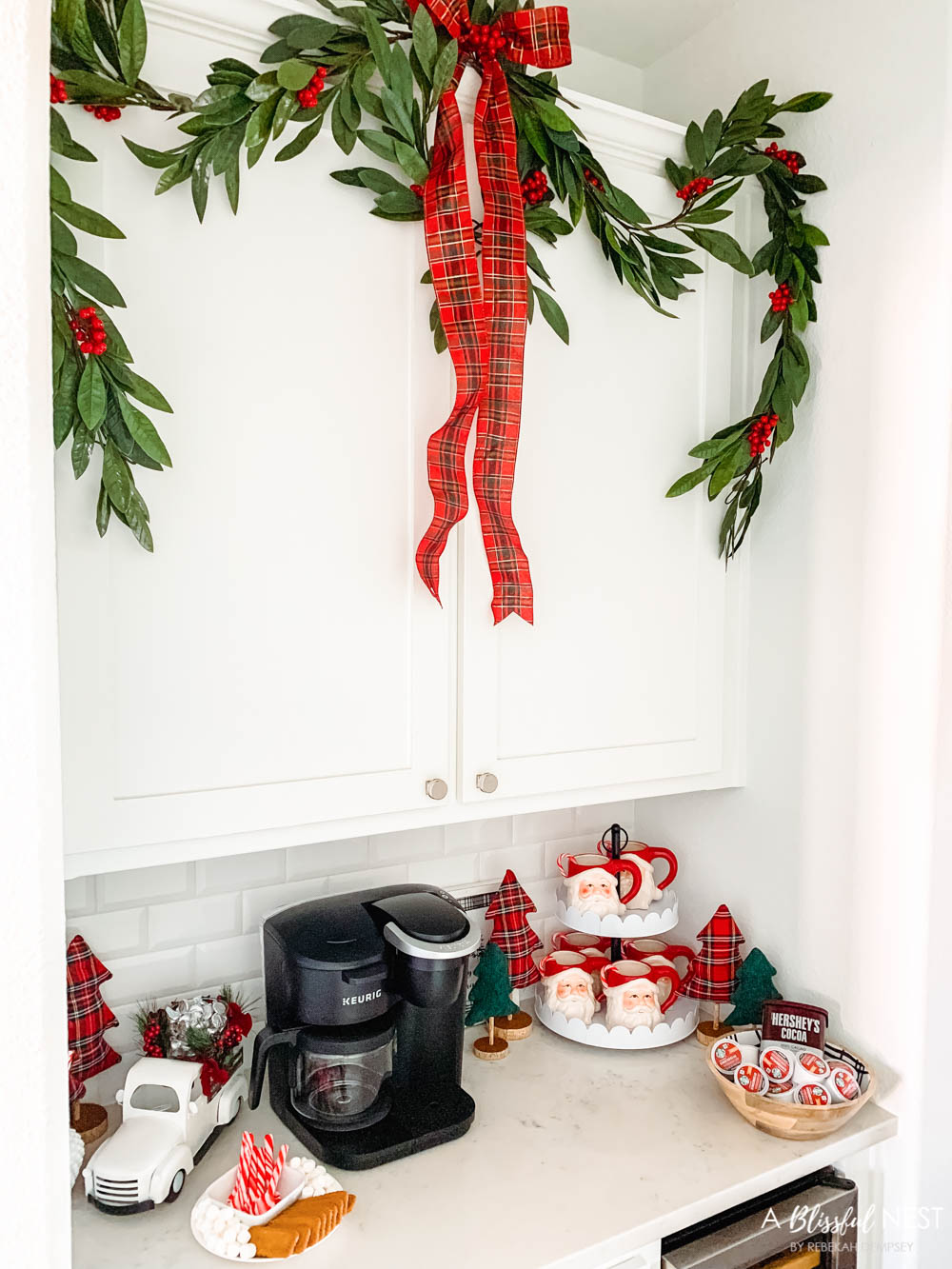 A hot cocoa station in a butlers pantry with santa mugs, graland and a Keurig machine.