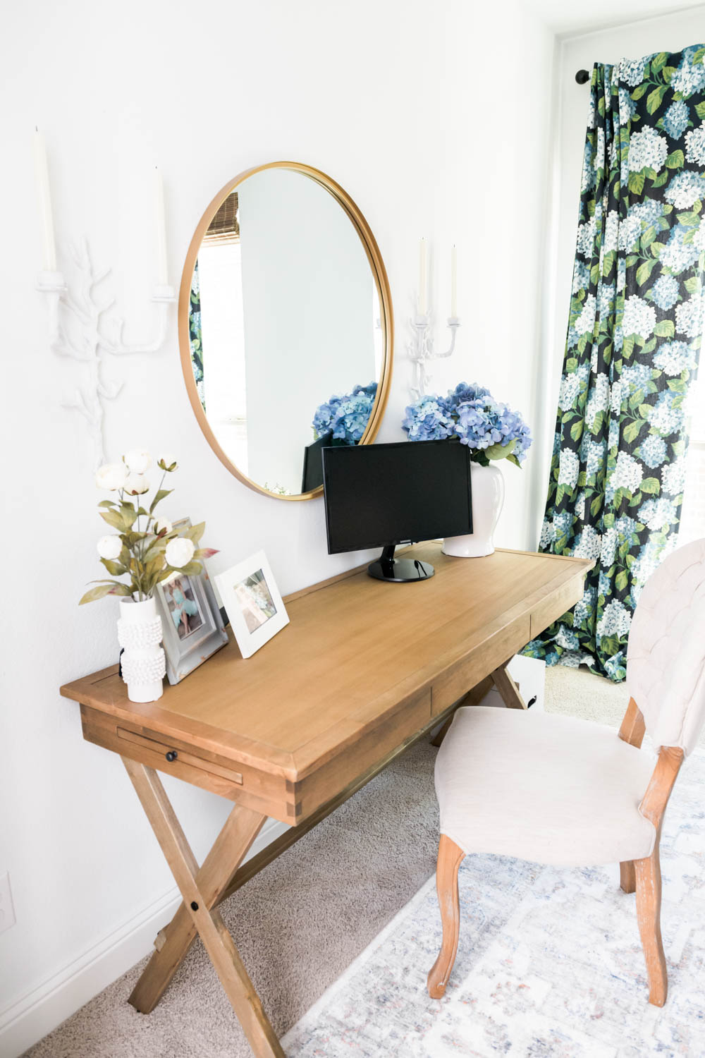 Round mirror above a wood desk adds light to a small home office space.