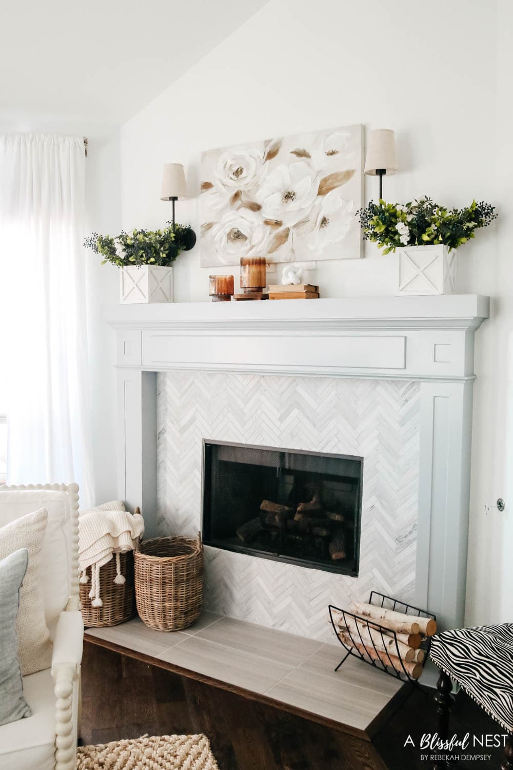 Living room view of a neutral spring mantle. Magnolia artwork above fireplace with white garden boxes with faux berry and white roses.