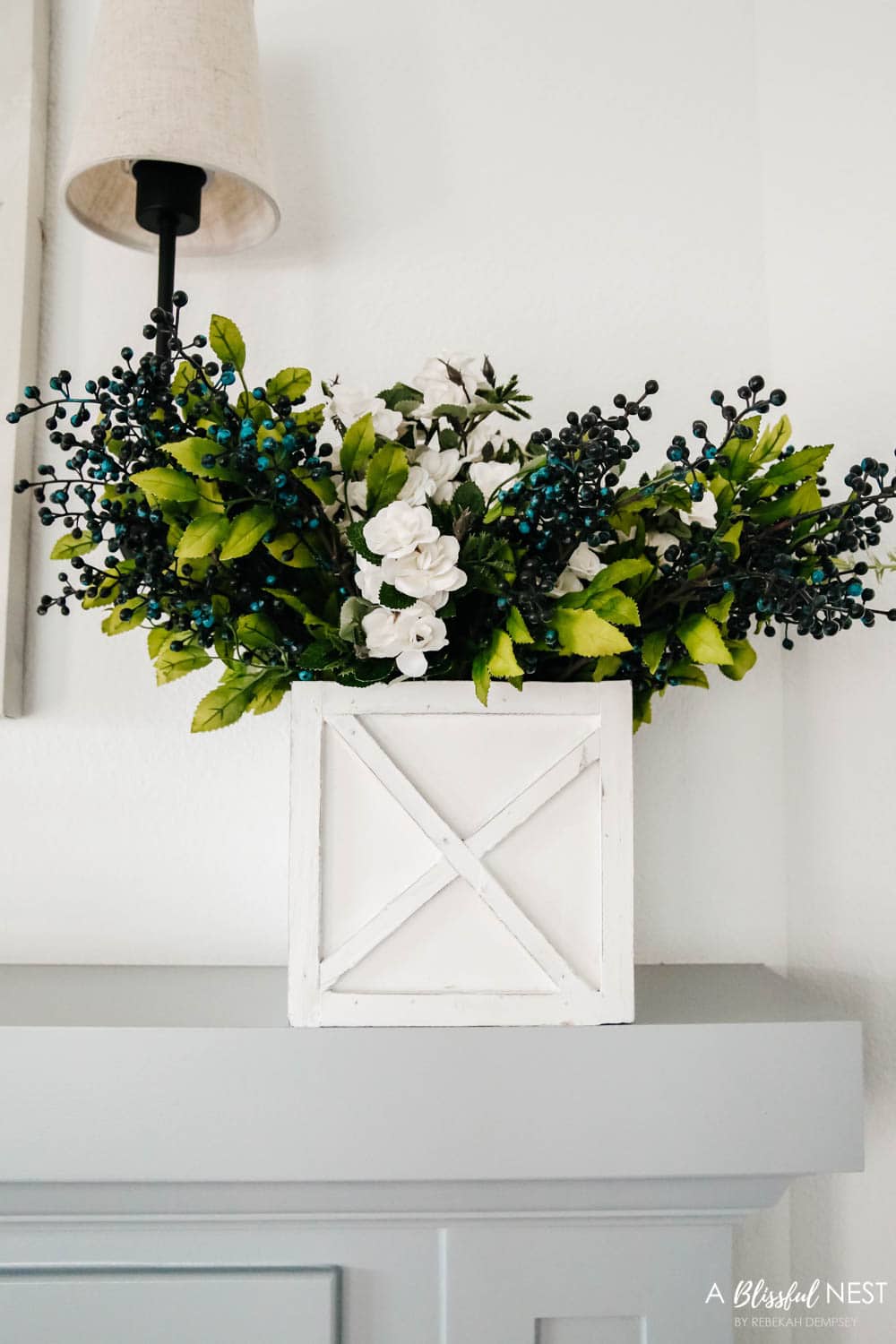 White square box planter with faux berry picks and faux white roses inside. 