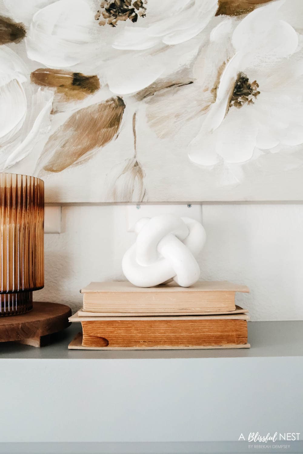 Decorative white ceramic knot sitting on top of vintage books.