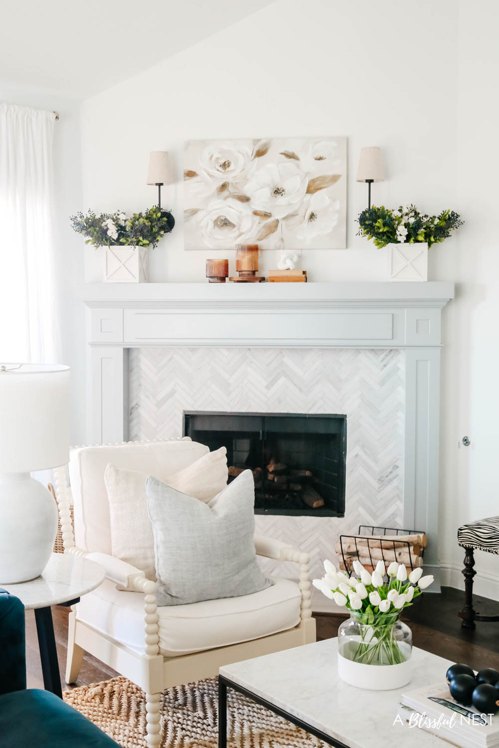 Living room view of a neutral spring mantle. Magnolia artwork above fireplace with white garden boxes with faux berry and white roses.