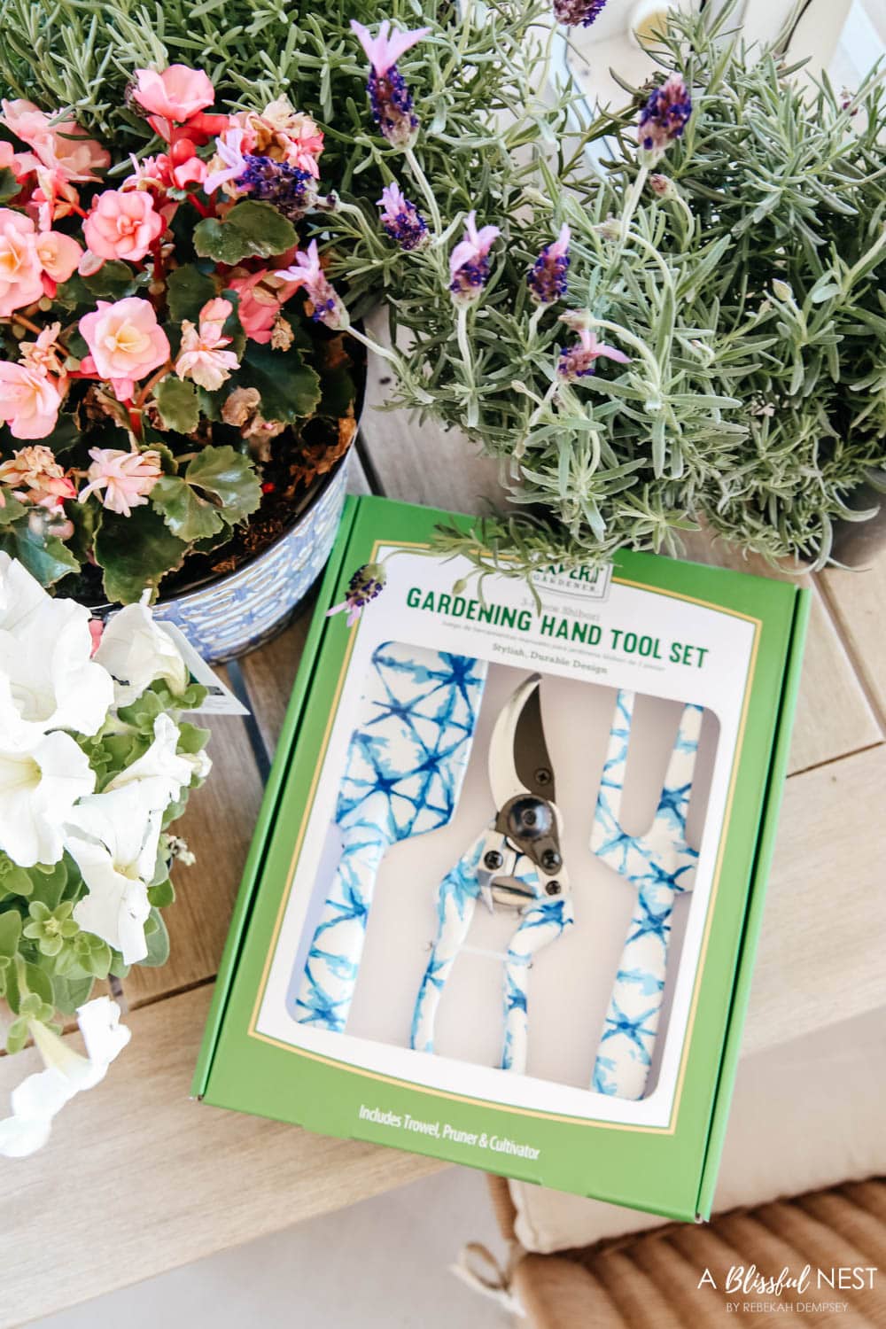 Blue and white gardening set on a patio table next to floweres