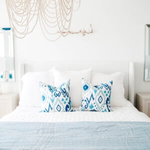 Blue and white ikat patterned pillows on a bed with white bedding