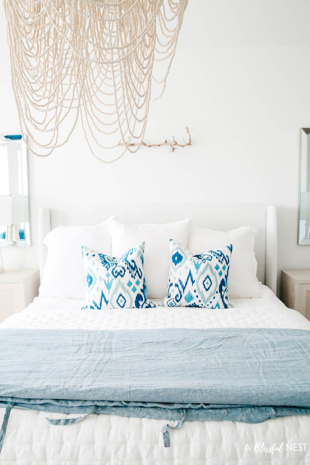 Blue and white ikat patterned pillows on a bed with white bedding