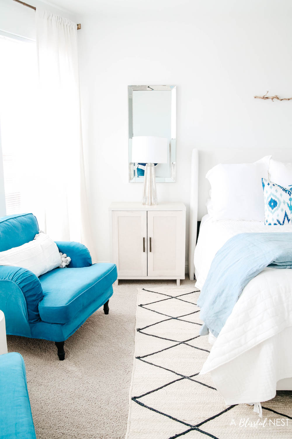 Nightstand with a mercury glass table lamp and a vertical mirror behind