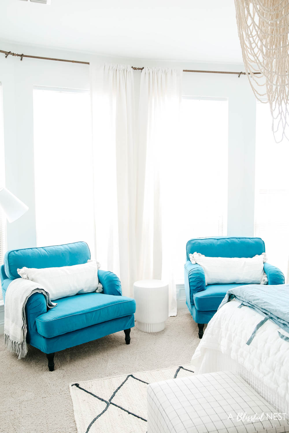 Two blue chairs in front of bay windows creating a cozy reading spot in a master bedroom