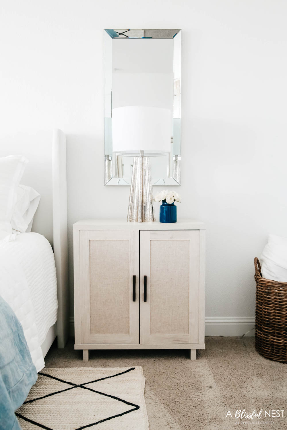 Nightstand with a mercury glass table lamp and a vertical mirror behind