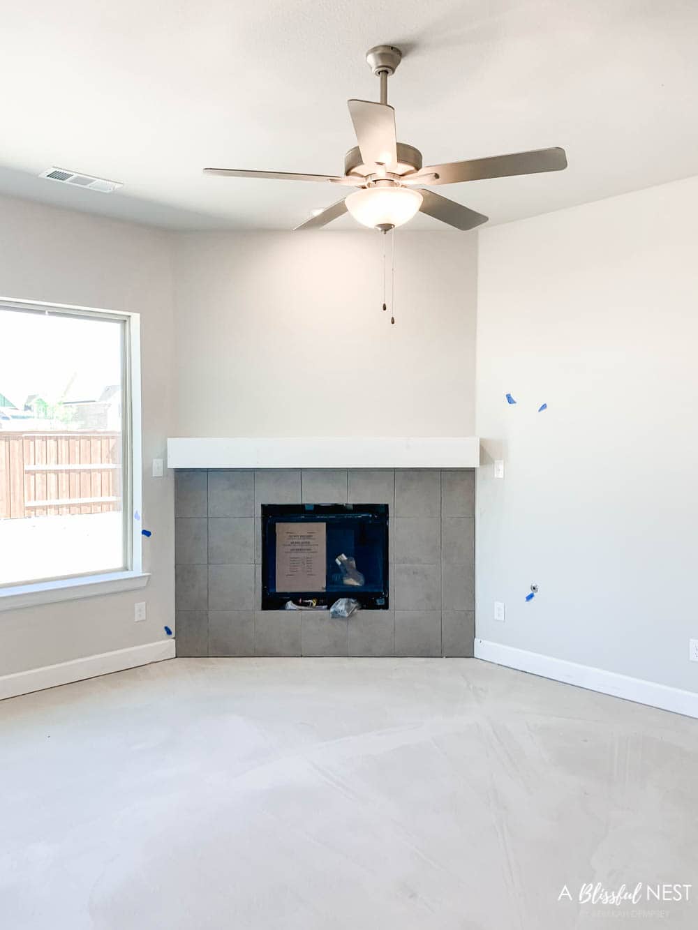 Grey square tile on facade of fireplace in living room.