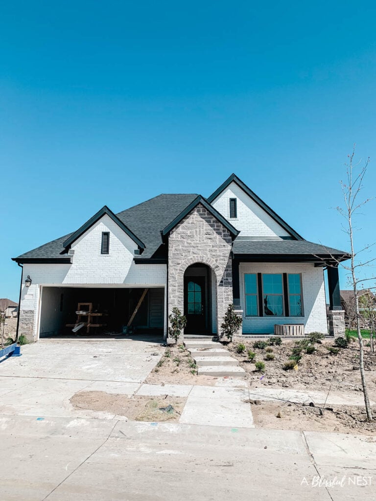 A darling small little new-build house that is white with black accents.