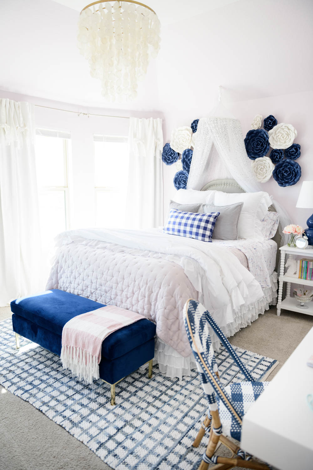 Lilac colored walls and blue and white flowers on the wall above the bed