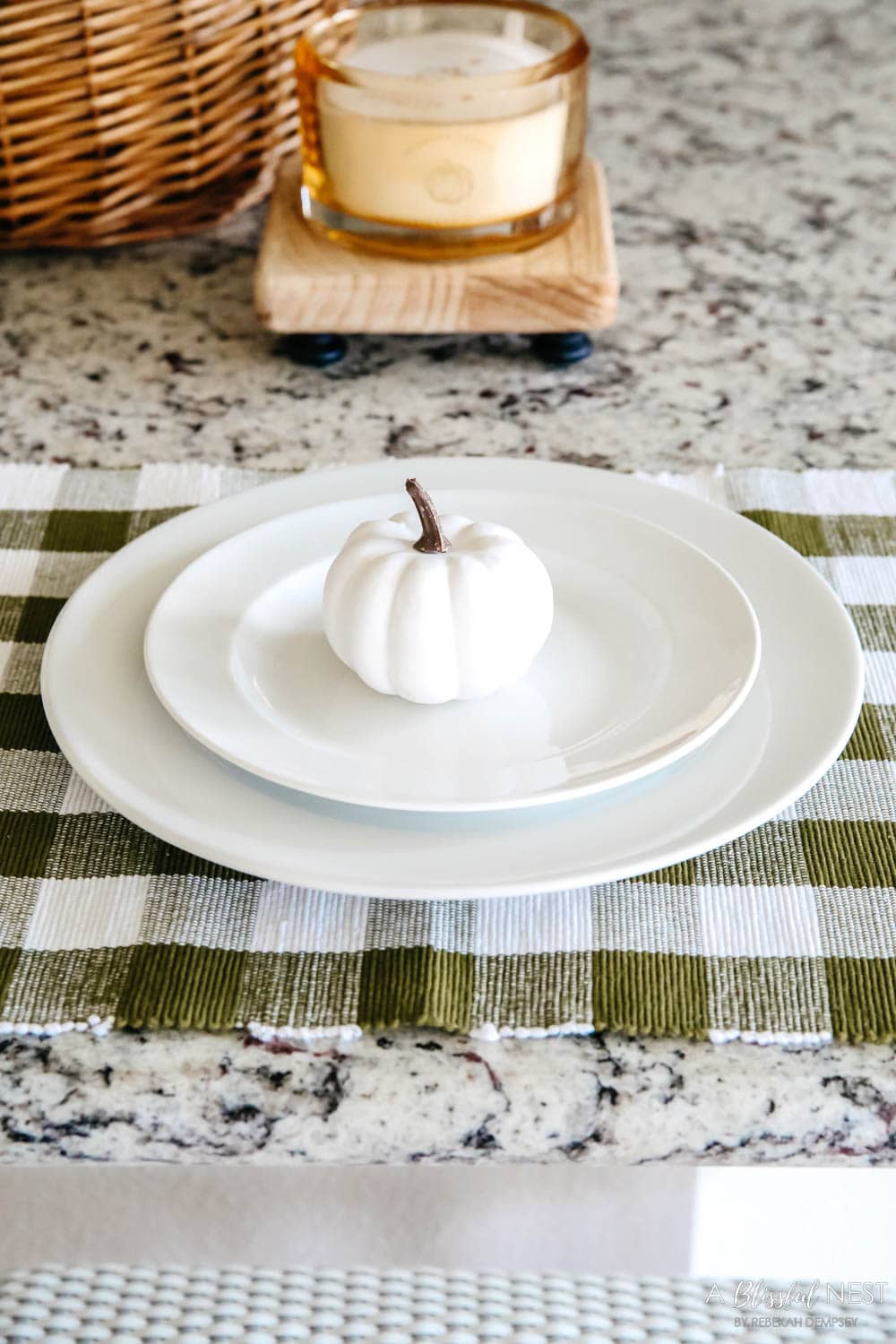 Mini white pumpkin on layered white plates on a green and white check placemat.