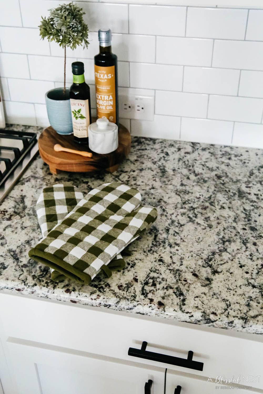 Green and white check oven mitts sitting on a counter top.