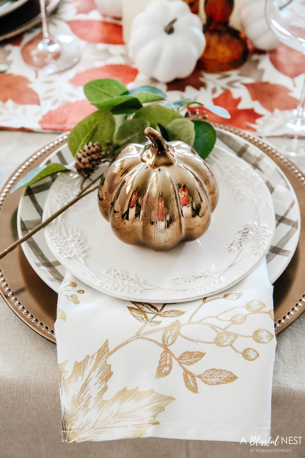 Close up of layered plates on a bronze charger with a bronze pumpkin