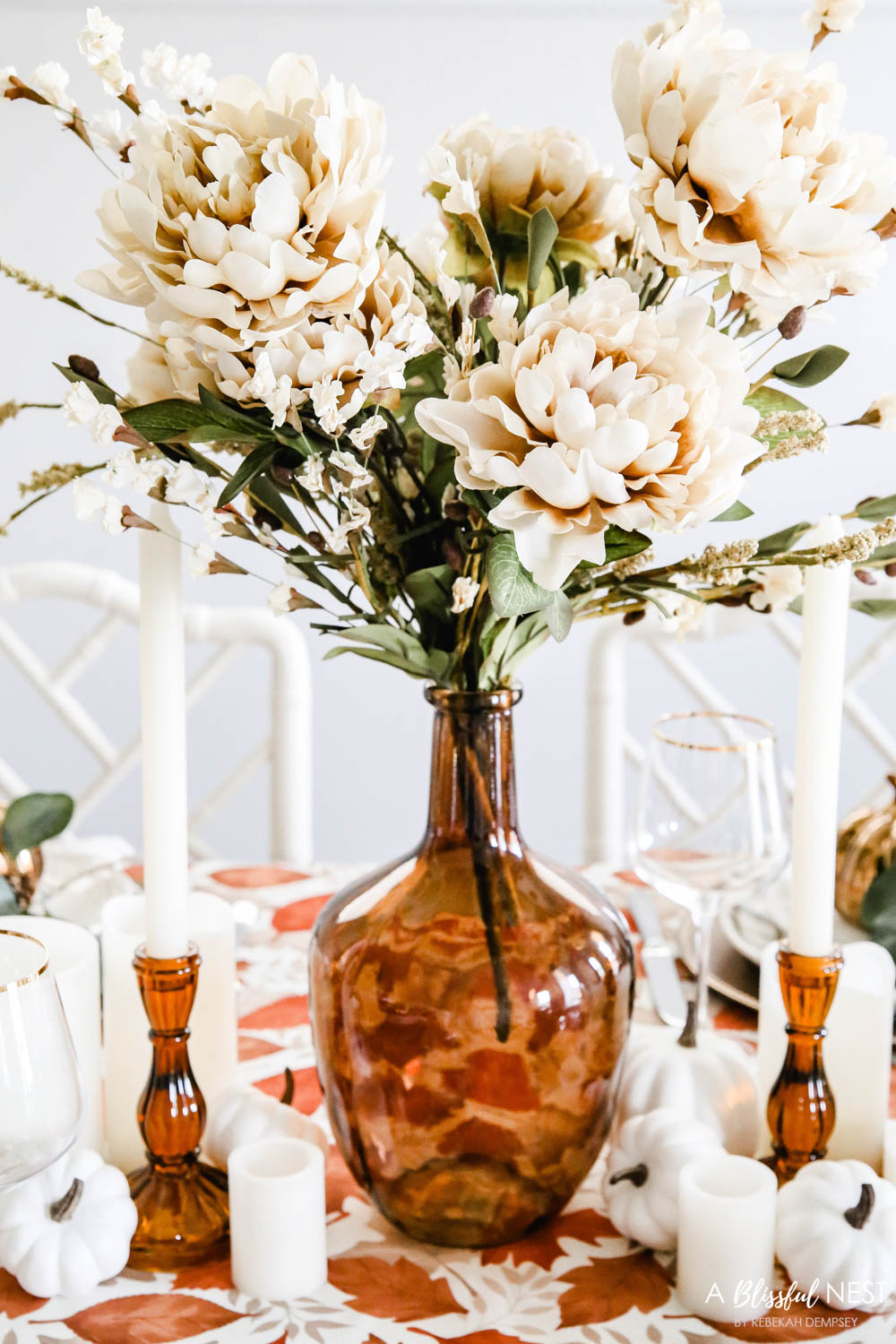 Amber colored vase with ivory colored flowers in the center of the table