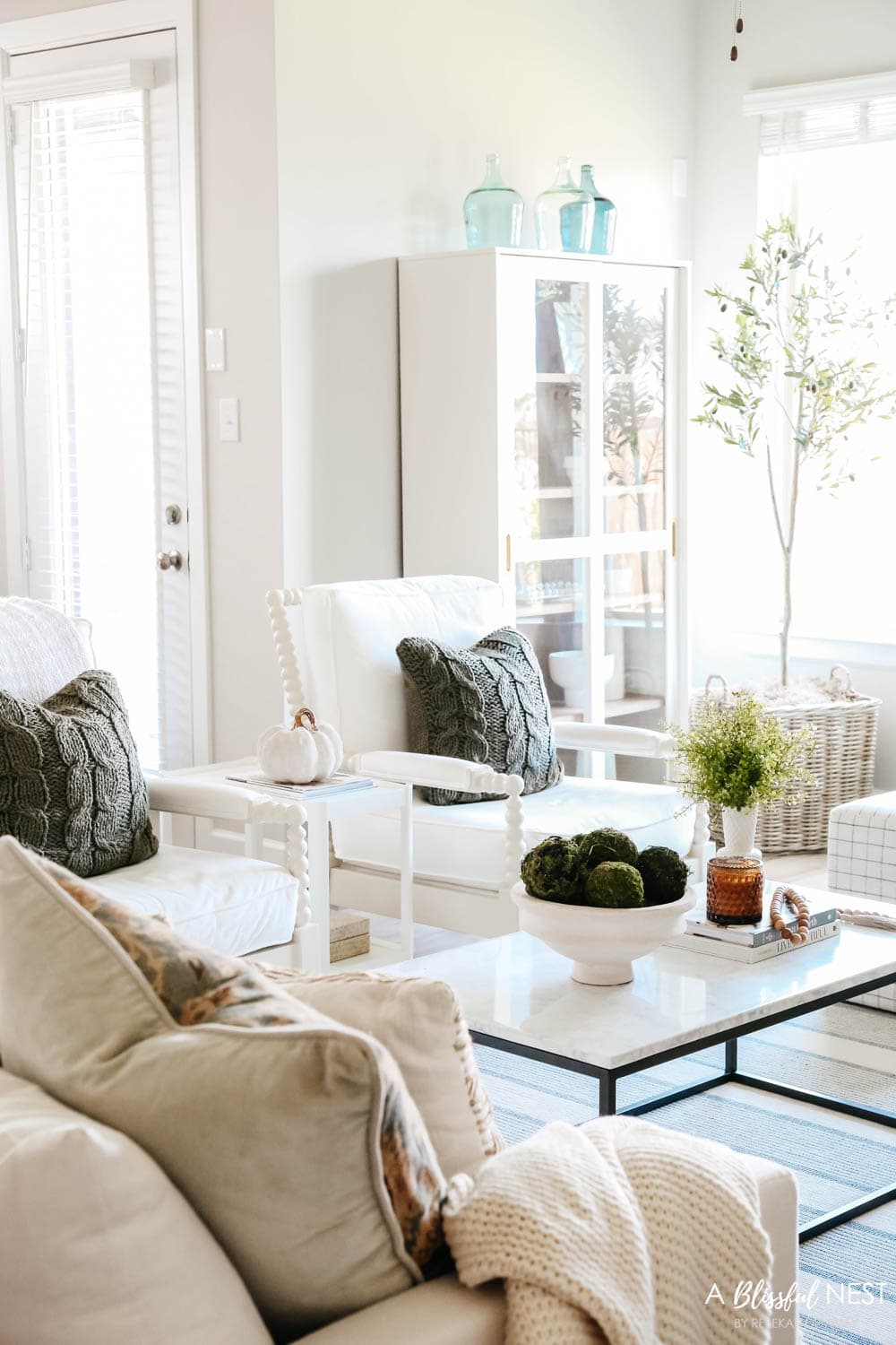 Olive green pillows on white spindle chairs in a living room decorating with fall accents