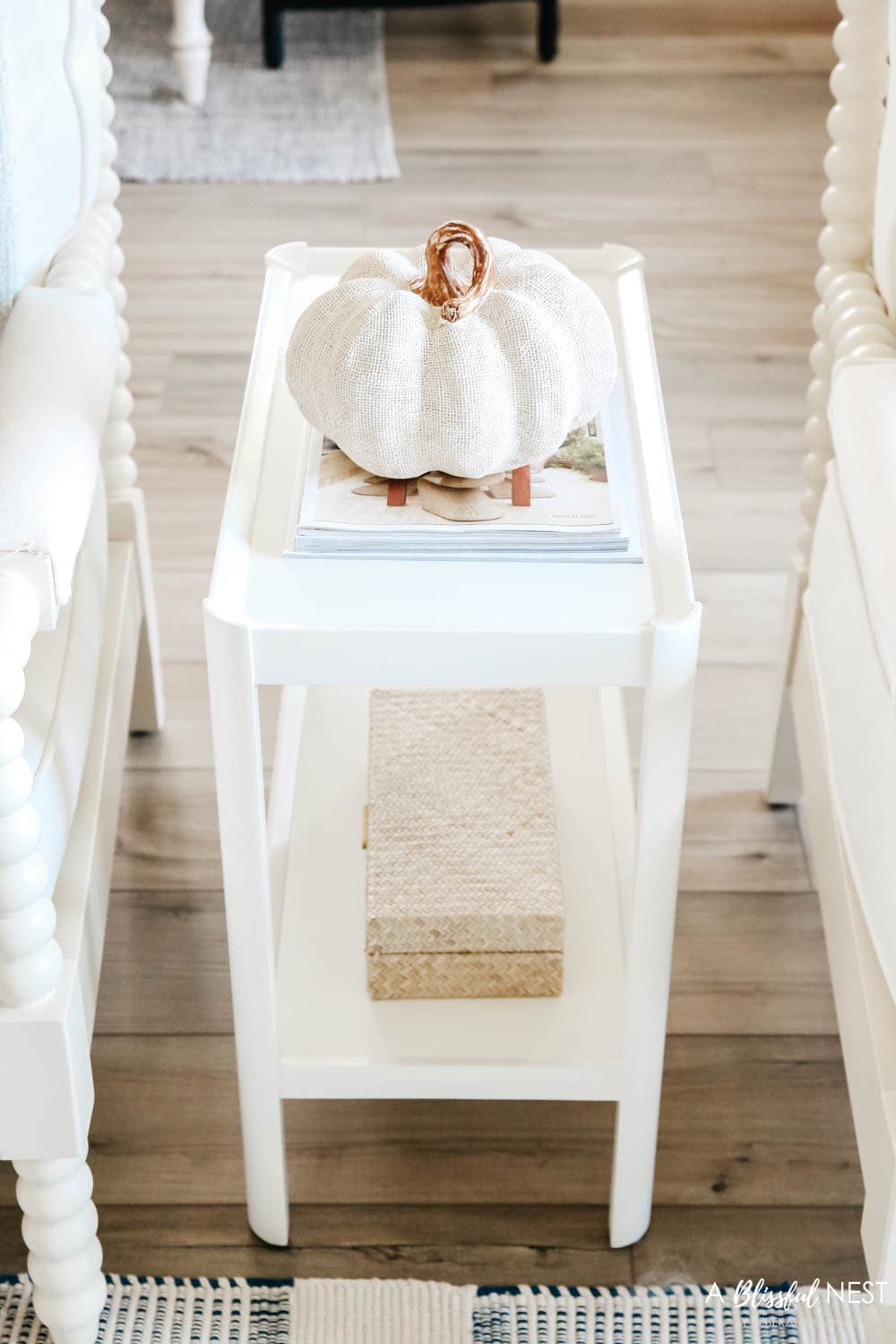 Linen textured pumpkin on small white side table next to living room chairs