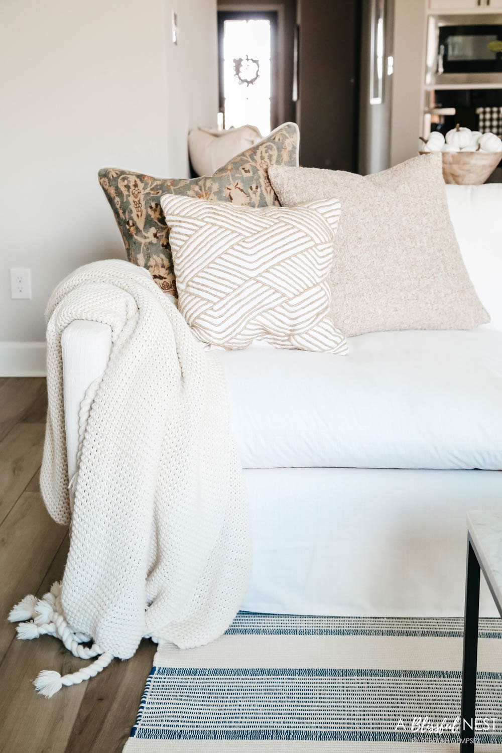 Fall hued pillows on cream colored sofa with a chunky knit blanket
