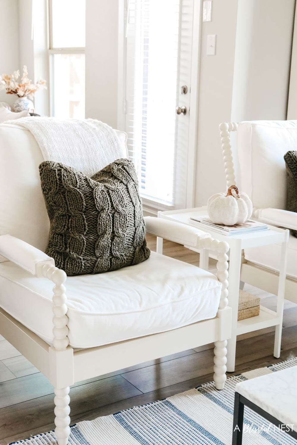 White spindle chairs with cozy olive green pillows