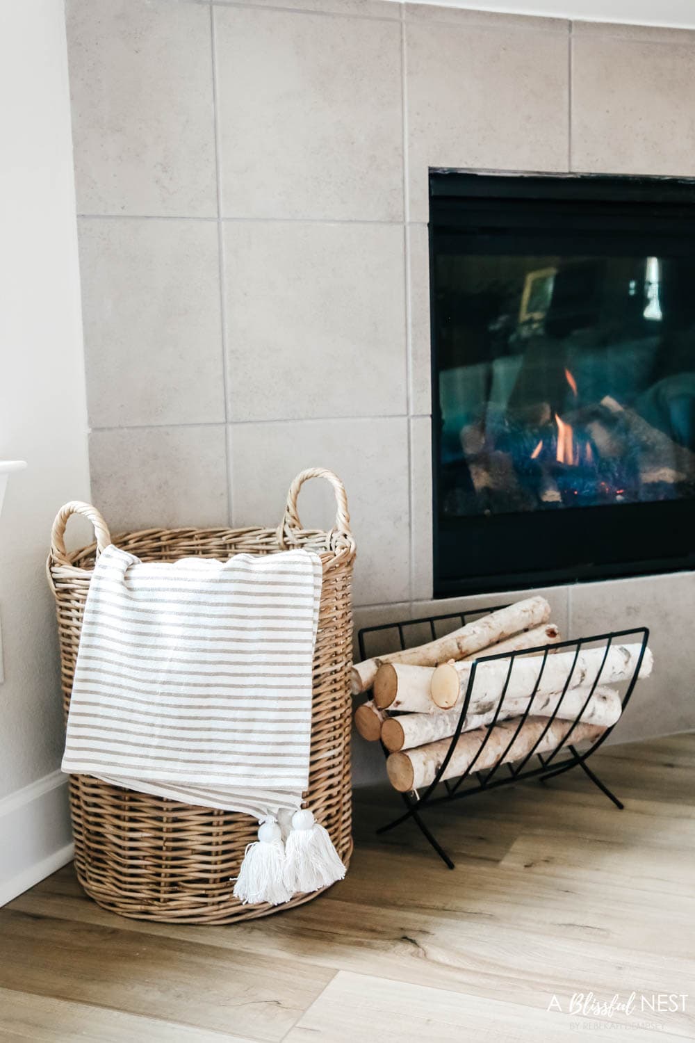 A basket filled with blankets and a metal log holder next to the fireplace