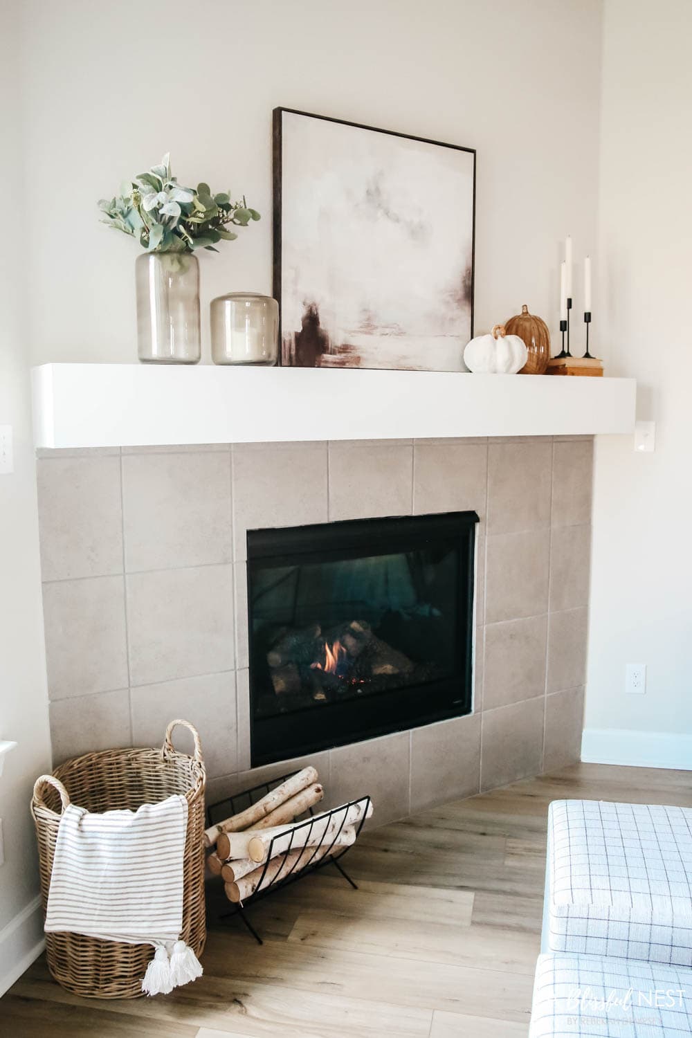 A basket filled with blankets and a metal log holder next to the fireplace