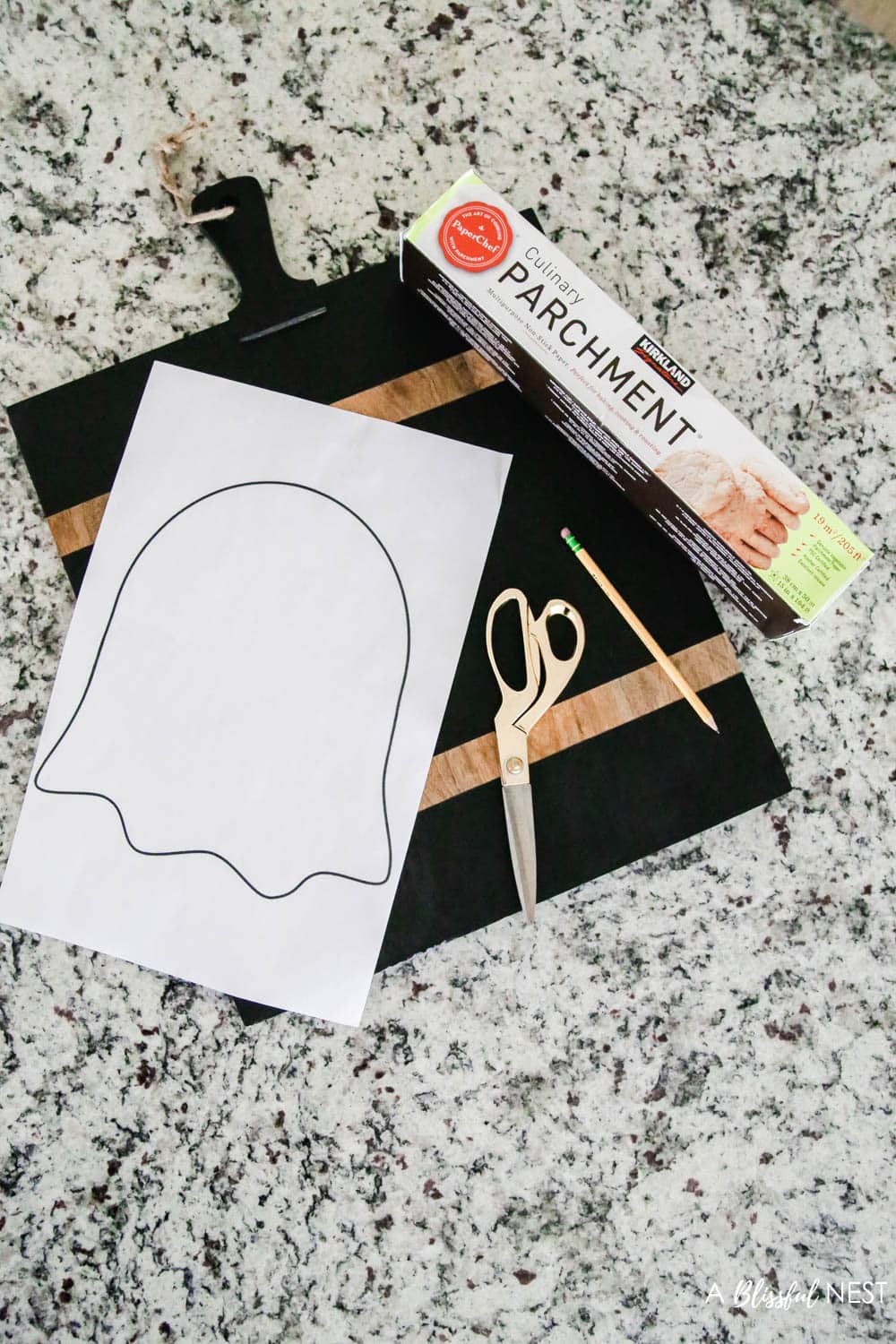 Black cutting board, ghost outline on paper to cut out, scissors, and parchment paper