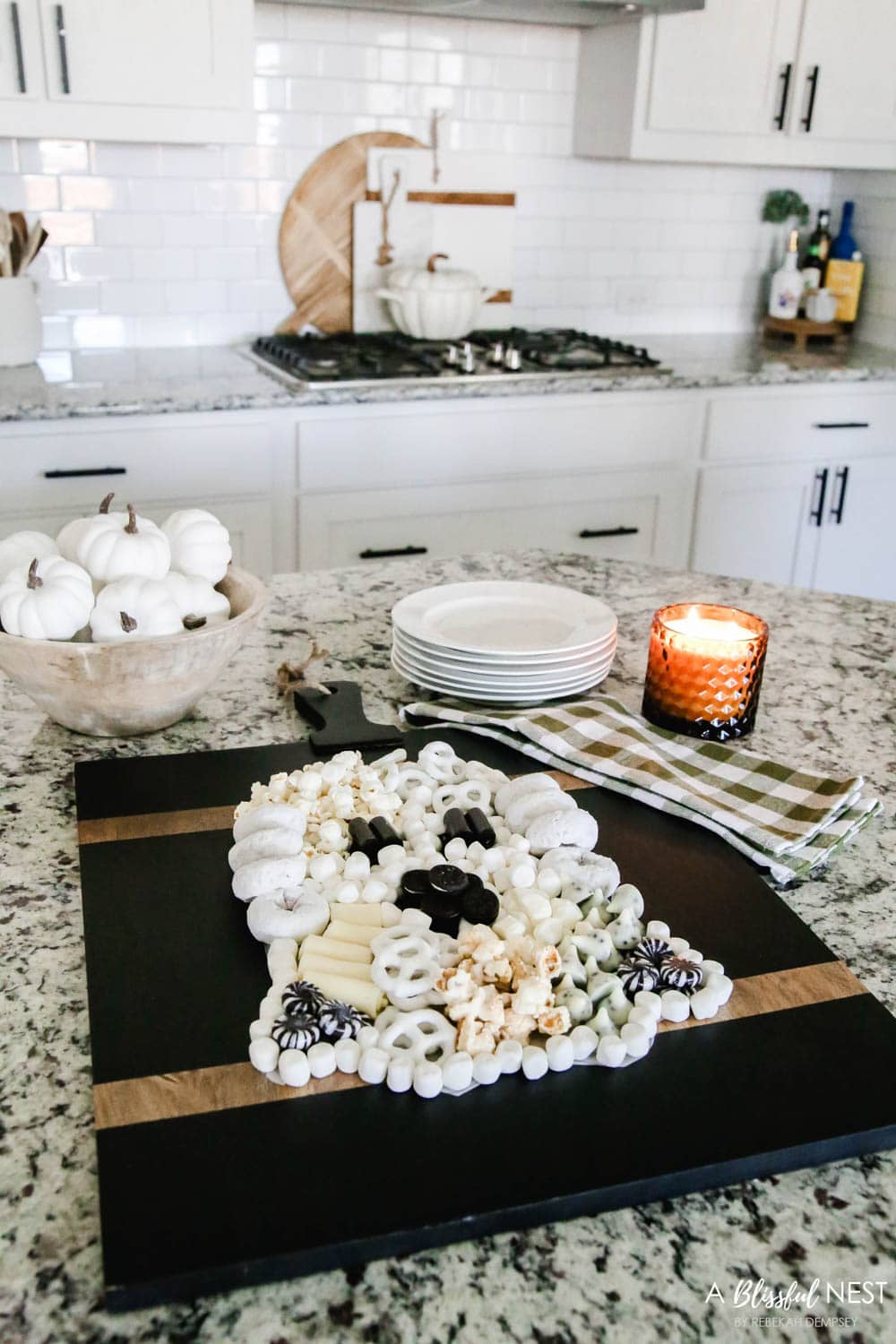 A black cutting board with sweet treats and cheeses laid out to look like a Halloween ghost.