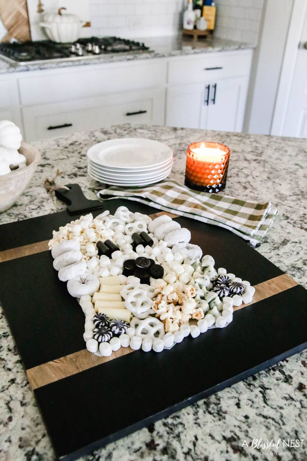 A black cutting board with sweet treats and cheeses laid out to look like a Halloween ghost.