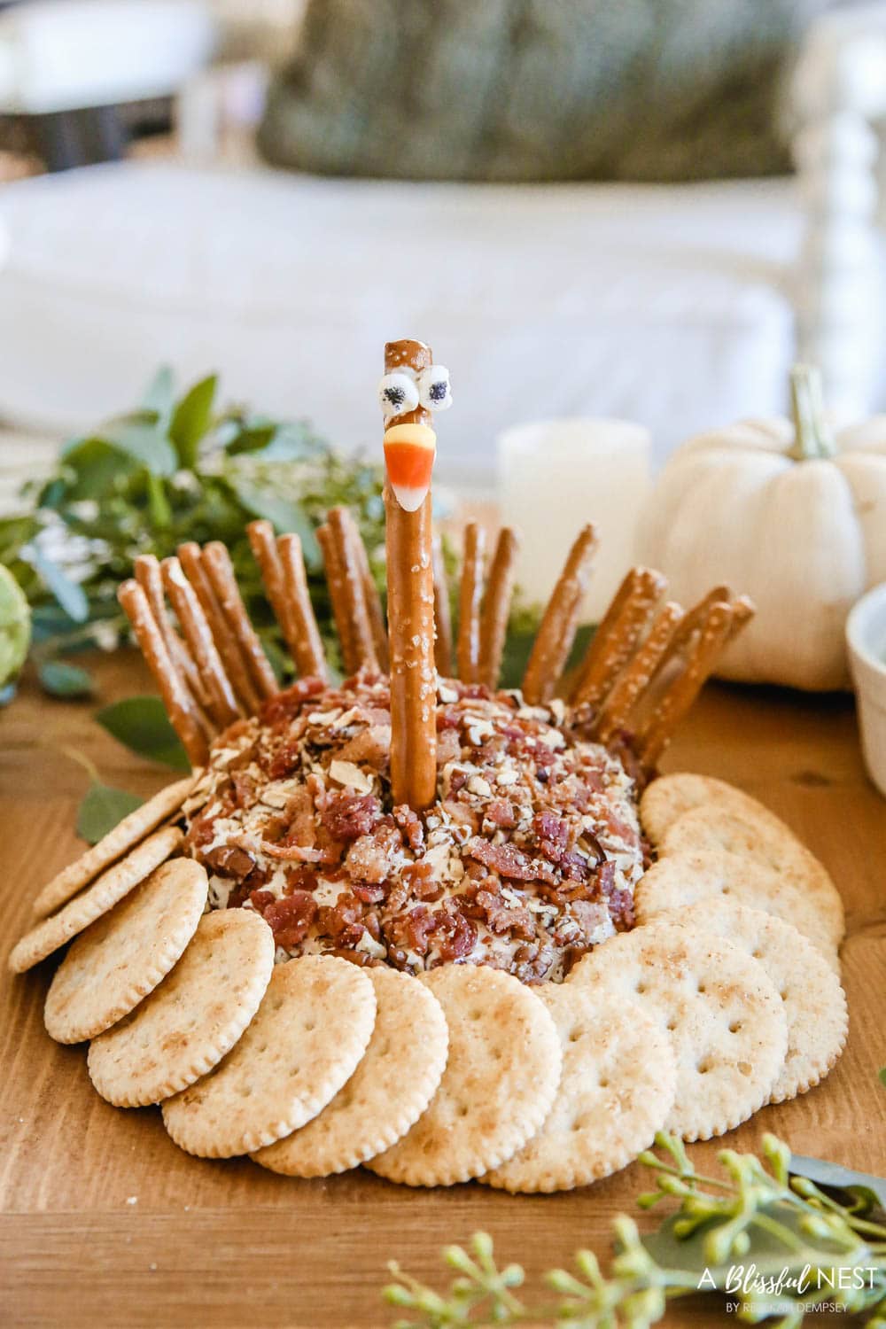 A cheese ball covered in crushed nuts with pretzels used as the feathers and a candy corn for the nose to create a turkey