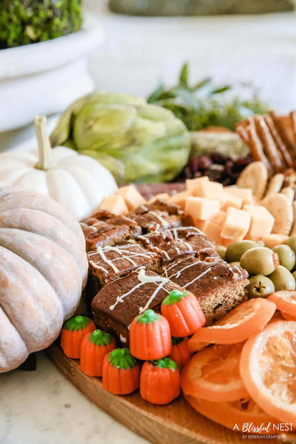 Mini pumpkin candies with pumpkin bread on a charcuterie board.