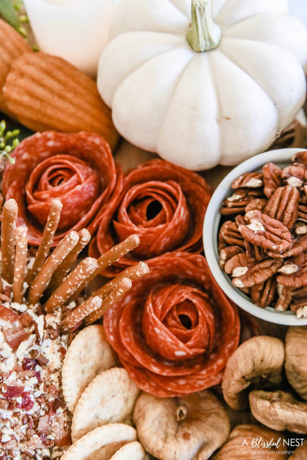 Salami rolled into rosebuds next to a bowl of pecans.