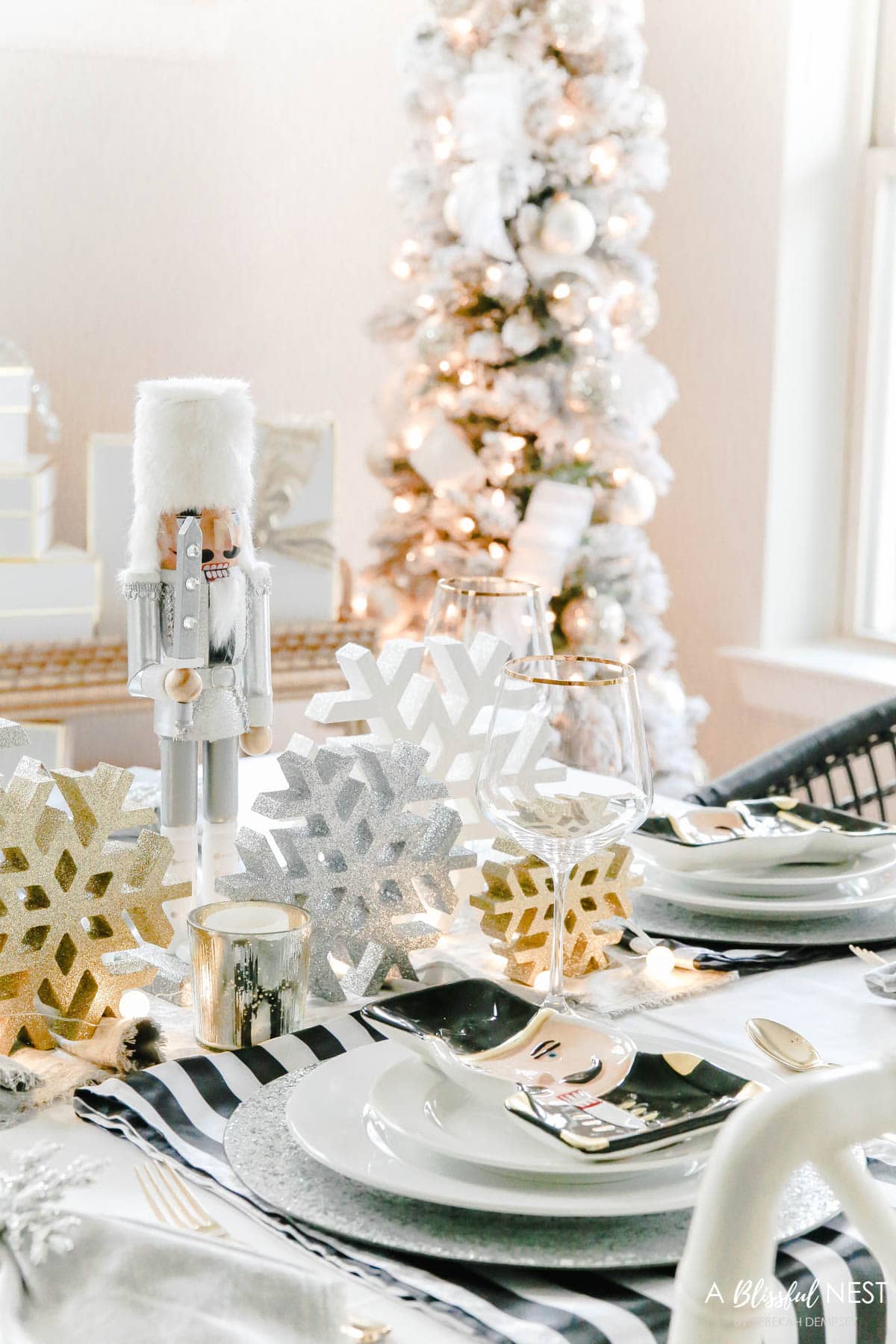 Black, white, and gold Christmas table decor including white plates mixed with nutcracker decor