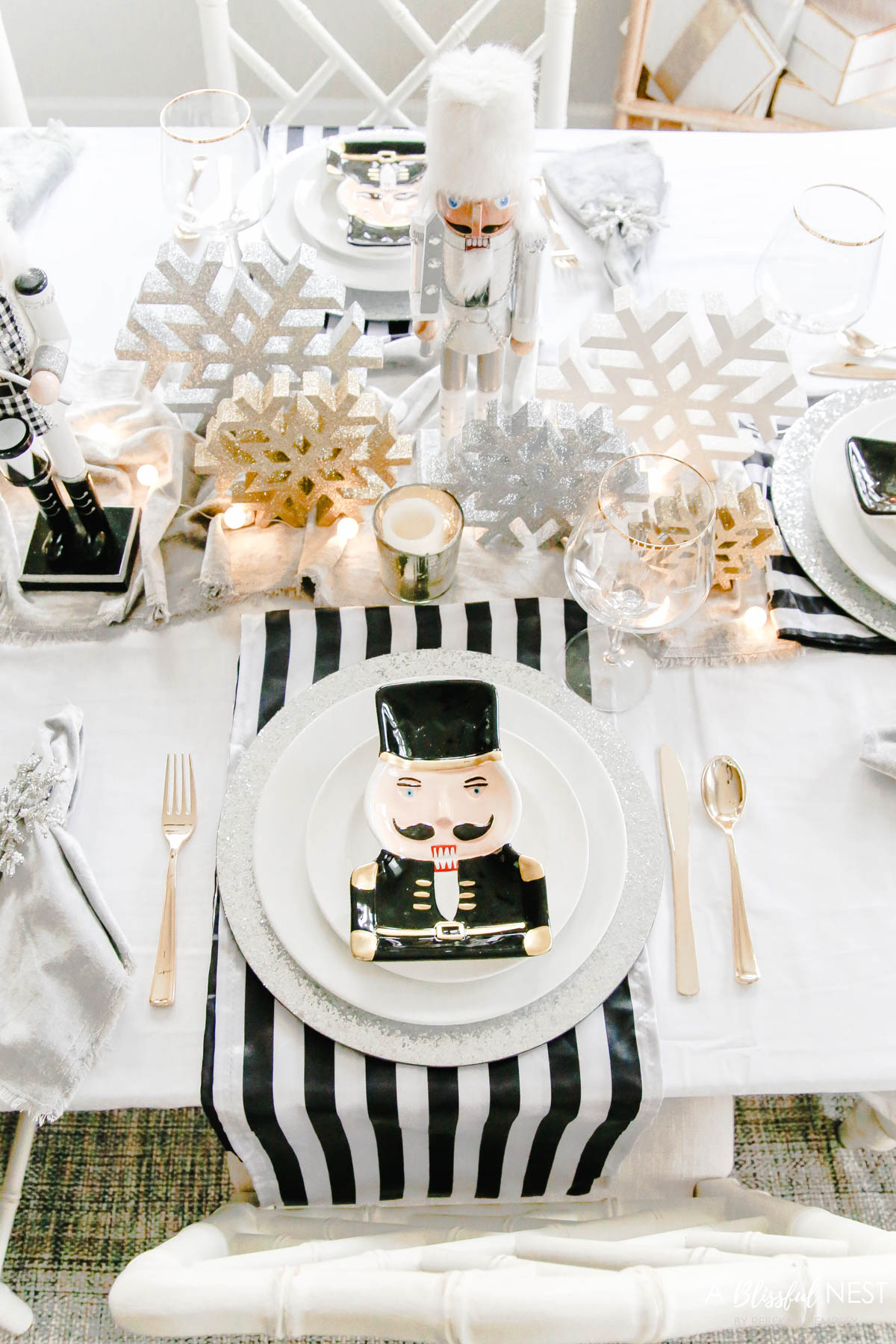 Black and white stripe fabric layered under a silver glitter charger with white dishes and a accent nutcracker dish on top