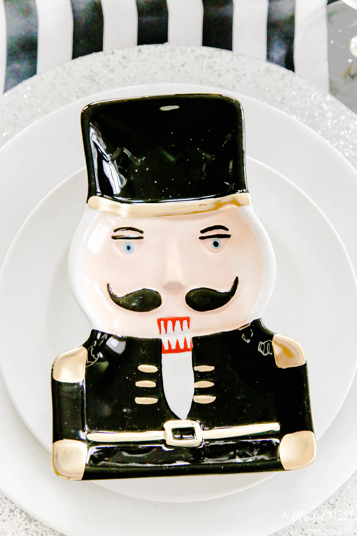 Black and white nutcracker plate sitting on top of white dishes