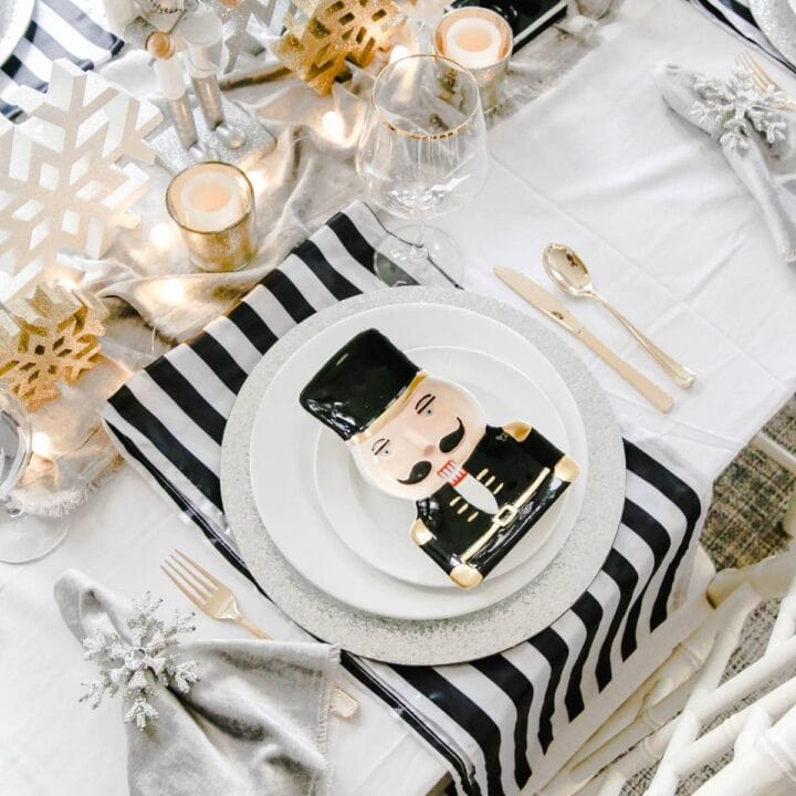 gold glitter snowflakes and gold votives in the center of the table with black and white fabric runner