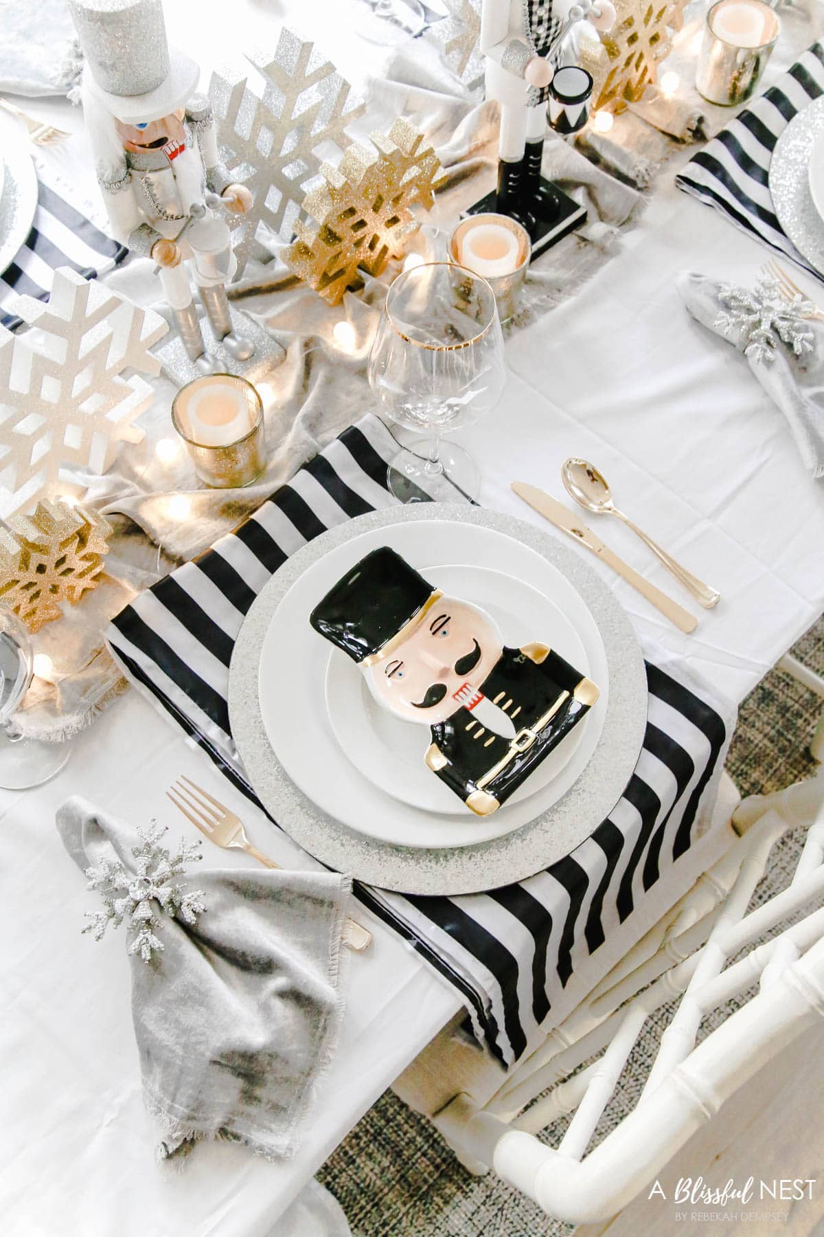 gold glitter snowflakes and gold votives in the center of the table with black and white fabric runner